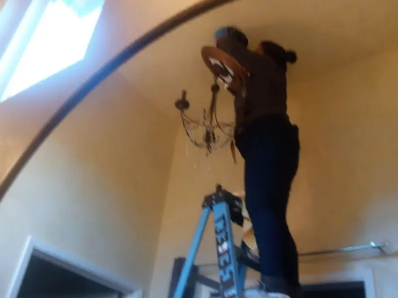 Electrician installing a chandelier in a Hidden Springs residence